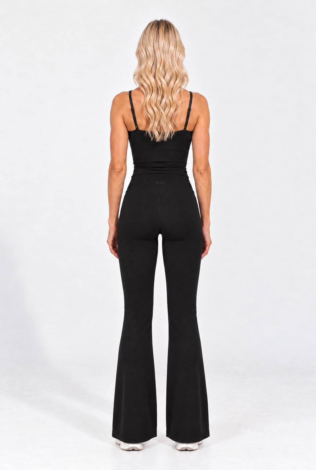 Back view of a black organic cotton cami top with flare leggings.