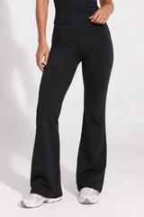 Woman wearing black organic cotton high-waisted flare leggings and a matching cami top.