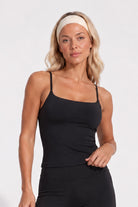 Woman wearing a black organic cotton cami top with matching flare leggings.