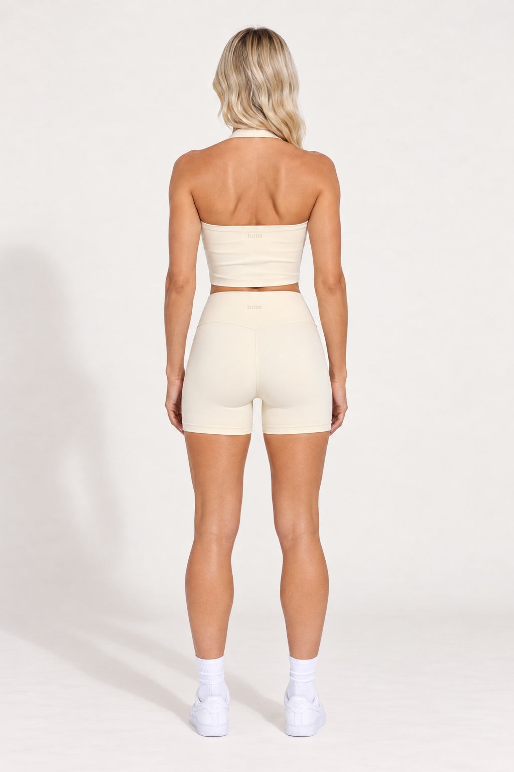 Back view of buttercream organic cotton high-waisted shorts with a matching halter top.