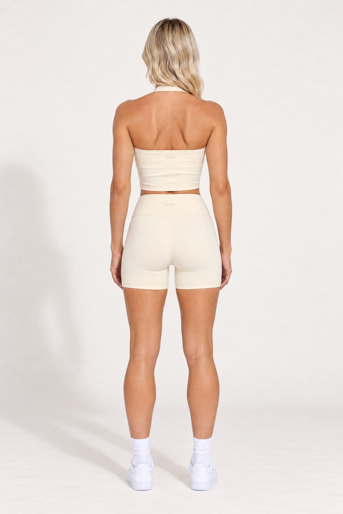 Back view of buttercream organic cotton high-waisted shorts with a matching halter top.