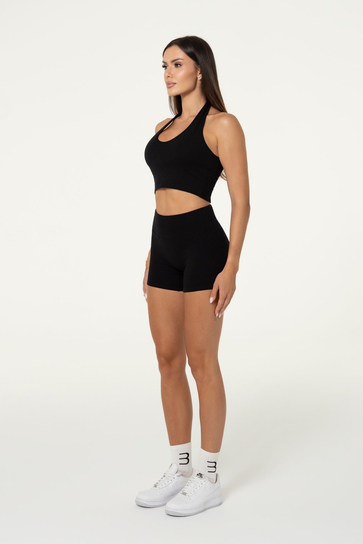 Woman wearing black organic cotton high-waisted shorts and a matching top.