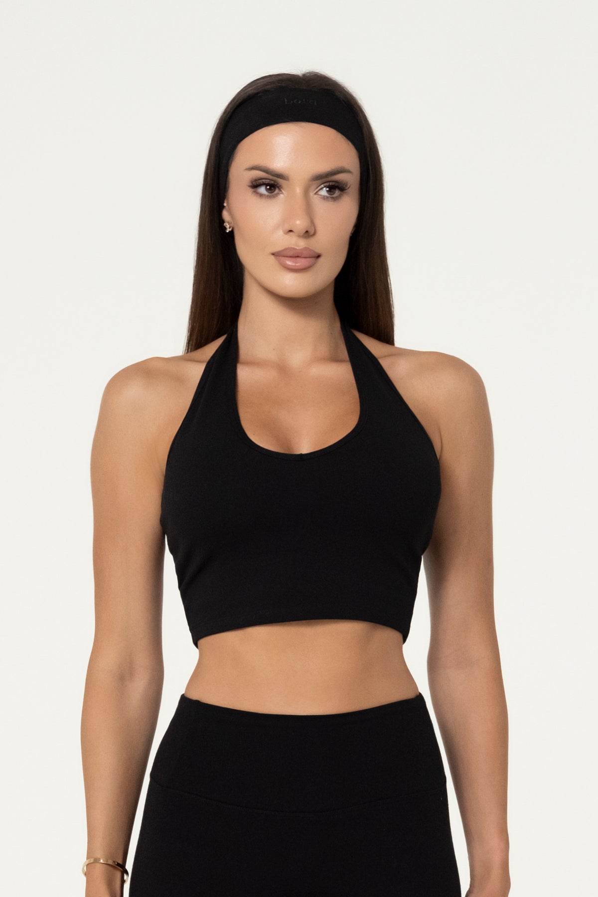 Woman wearing a black organic cotton halter top with matching leggings.