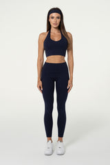 Woman wearing navy organic cotton halter crop top and high-waisted leggings.