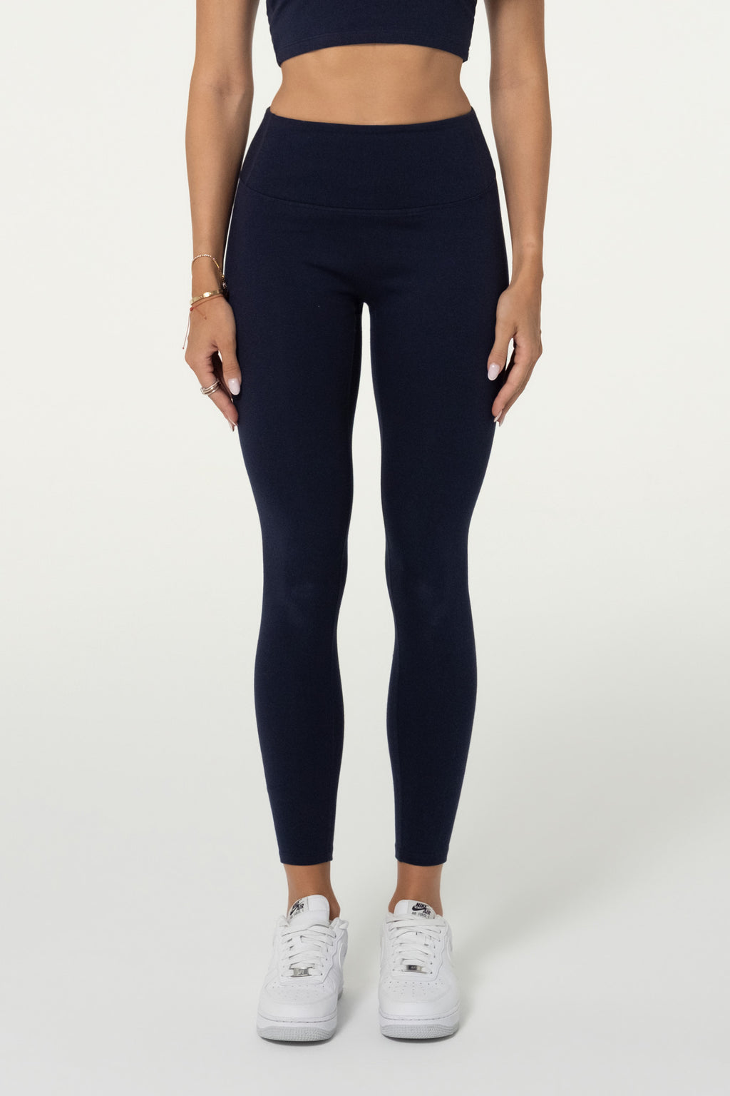 Model wearing navy organic cotton high-waisted leggings and matching halter top.