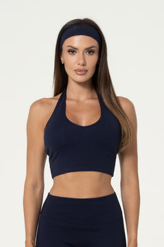 Woman wearing a navy organic cotton halter top with matching high-waisted leggings.