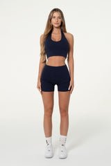 Front view of a woman wearing a navy organic cotton halter top.