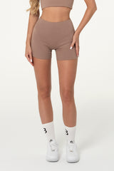 Woman wearing truffle brown organic cotton high-waisted shorts.