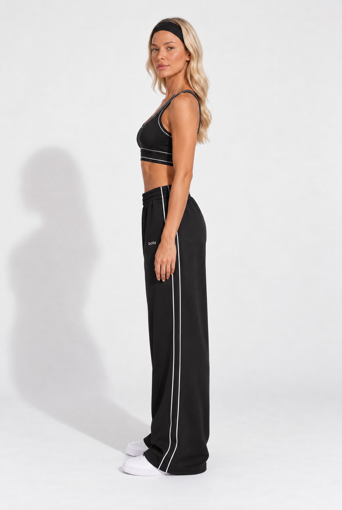 Woman wearing a black organic cotton sports bra with matching oversized sweatpants.