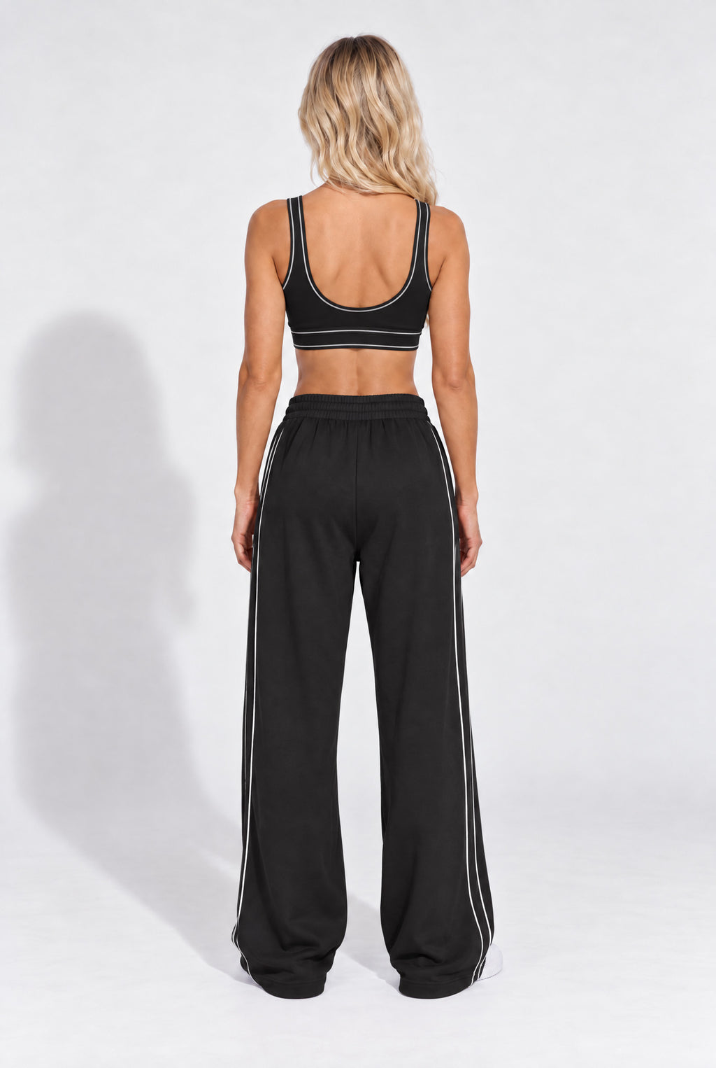 Black organic cotton sports bra worn with matching sweatpants, back view.