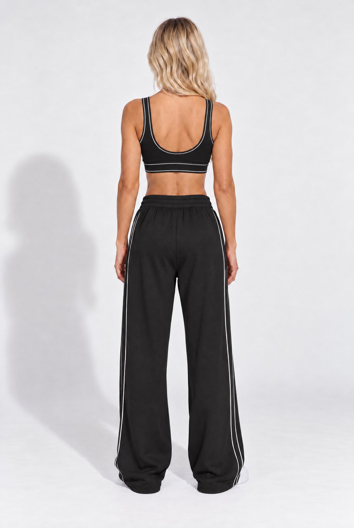 Black organic cotton sports bra worn with matching sweatpants, back view.