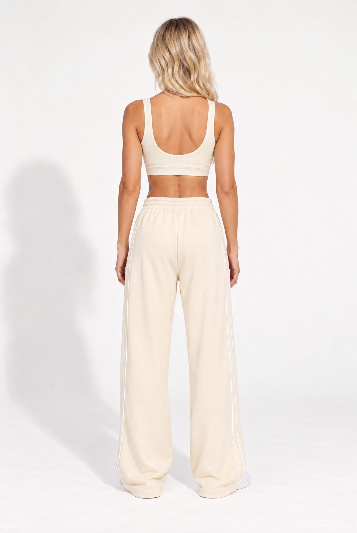 Back view of a buttercream organic cotton sports bra and oversized sweatpants.
