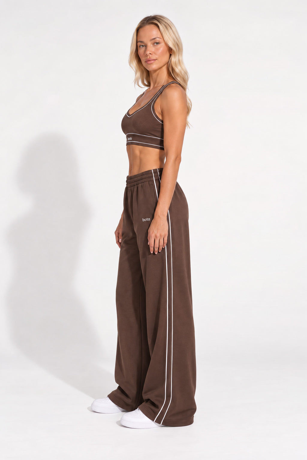 Woman wearing a chestnut brown organic cotton sports bra and oversized sweatpants.