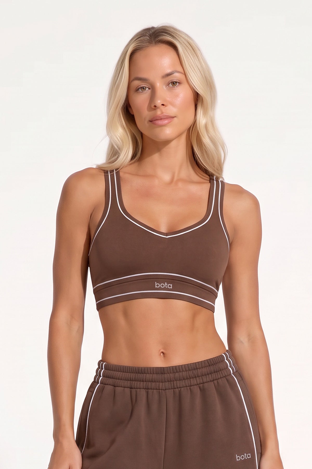 Woman wearing a chestnut brown organic cotton sports bra with matching oversized sweatpants.